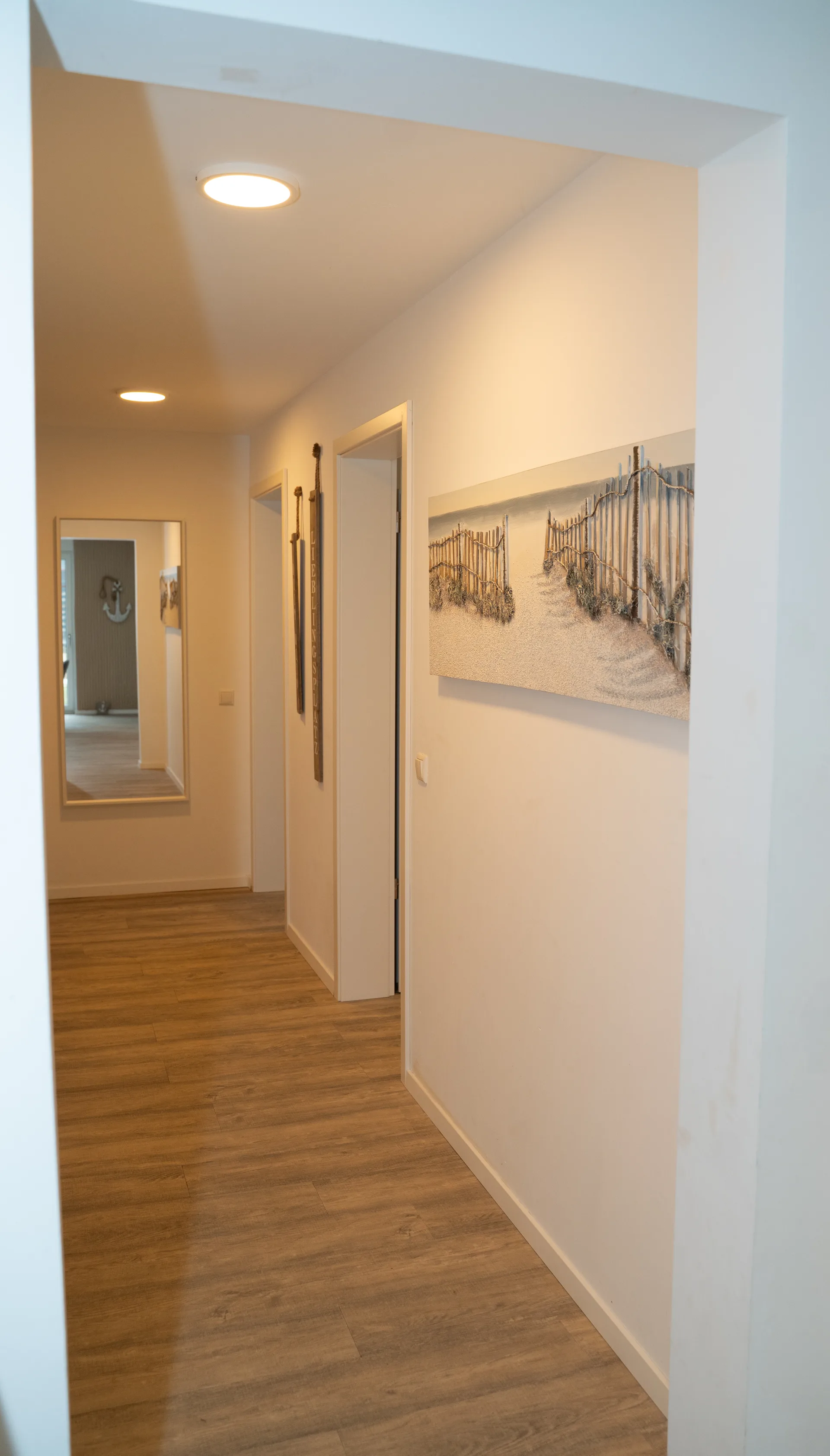 Flur der Ferienwohnung Kurparkperle mit Strandweg-Gemälde und dekorativem Spiegel