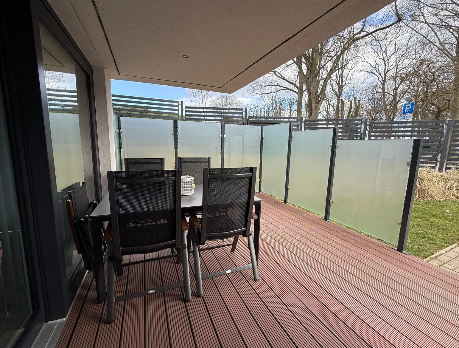 Gemütliche Sitzgruppe auf der Terrasse der Kurparkperle mit Glaswand-Windschutz und Gartenblick