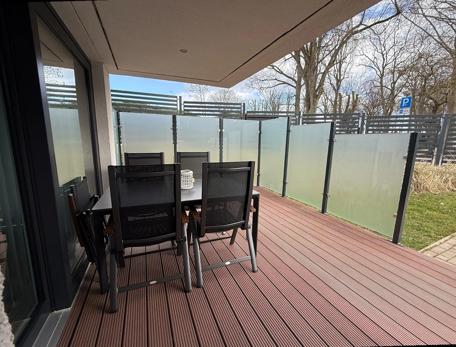 Überdachter Terrassenbereich mit Sitzgruppe und Milchglas-Sichtschutz an der Ferienwohnung Kurparkperle